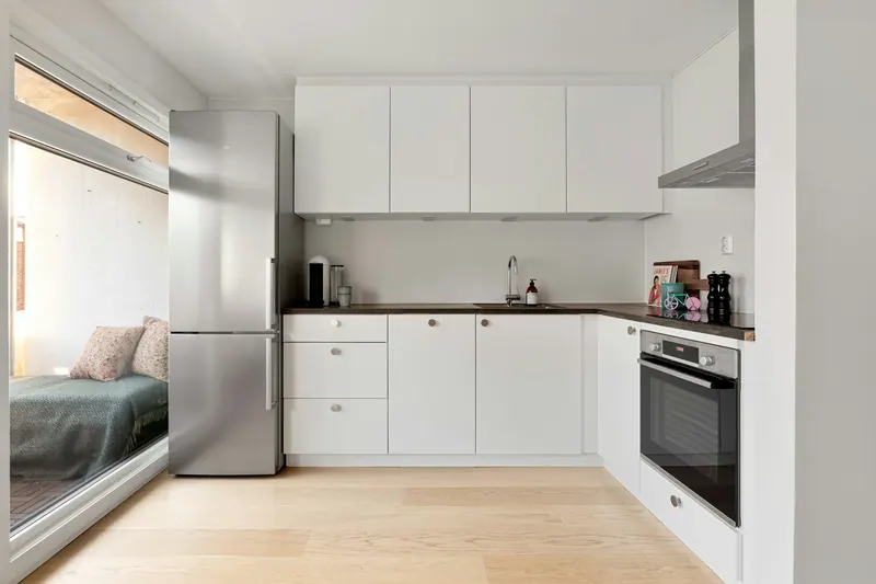 Compact studio with a white kitchen and light wood floor