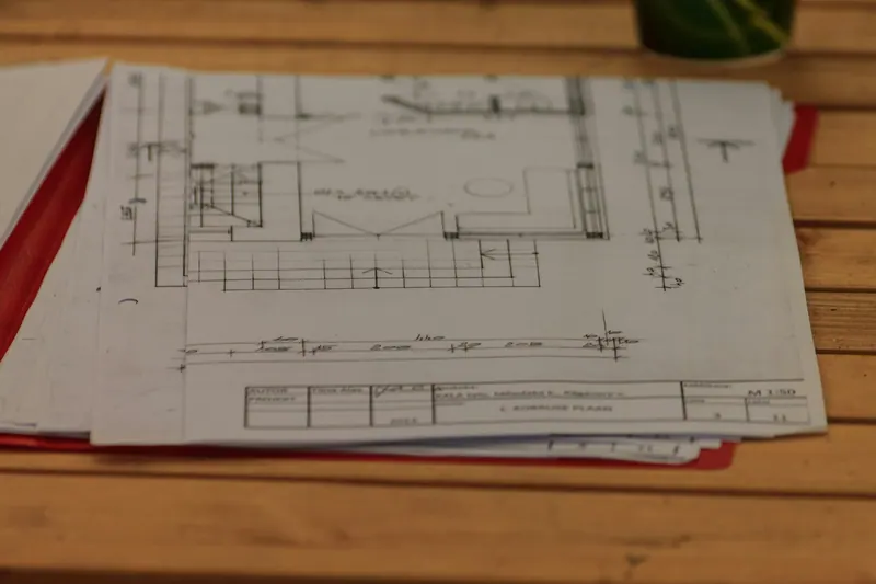 Stack of printed floor plans on a wood table