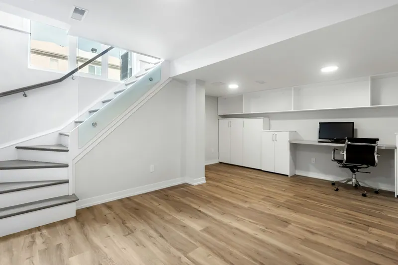 Finished basement with a glass-rail staircase, built-in storage and a desk