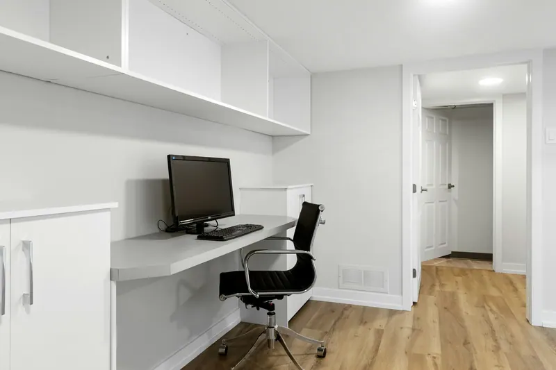 Finished basement office nook with built-in desk and cabinets