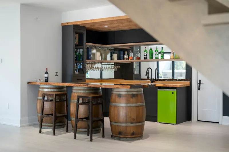 Basement bar with a wood counter and barrel stools under the stairs