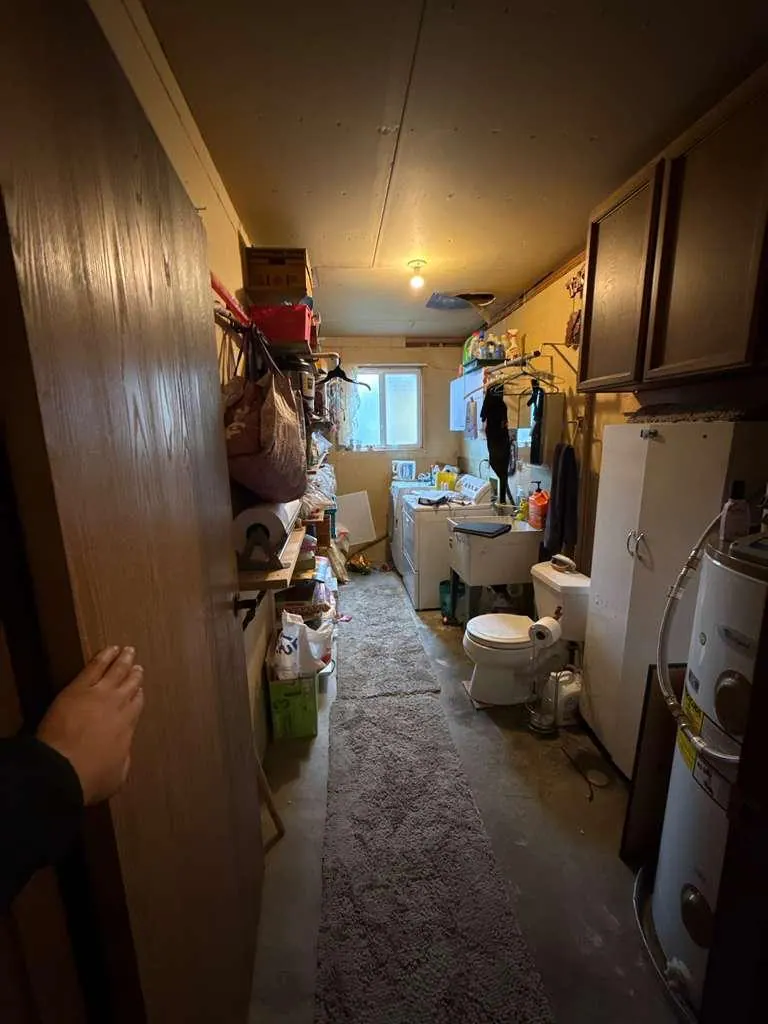 Before: The utility room before the conversion, with a toilet, laundry machines, a utility sink and water heaters