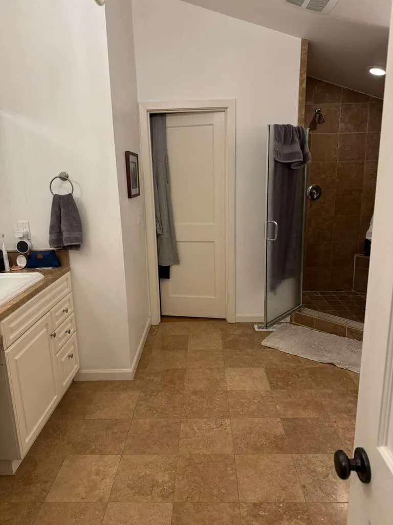 Before: The bathroom before the remodel, with brown travertine floor tile and a white vanity