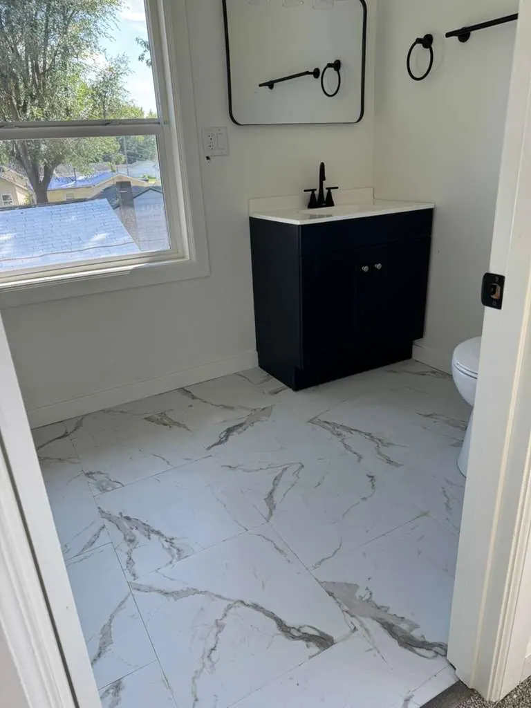 Small bathroom with marble-look floor tile, a navy vanity, a black faucet and a black-framed mirror