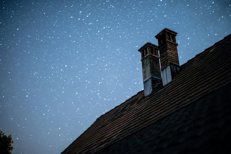 Chimneys on a roof under a night sky