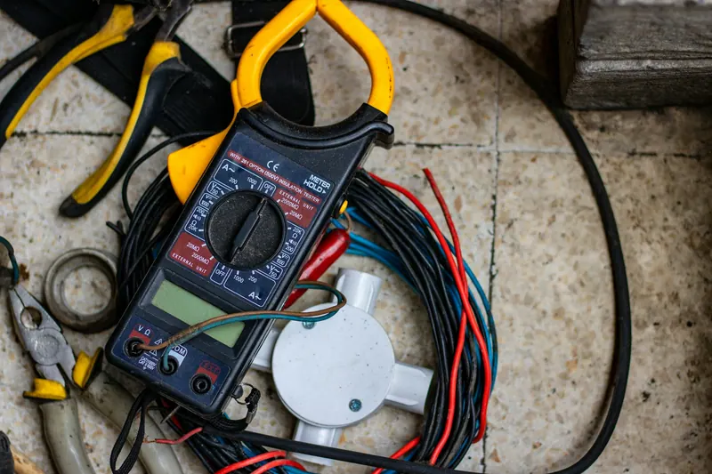 Clamp meter, pliers and wires laid out for electrical work