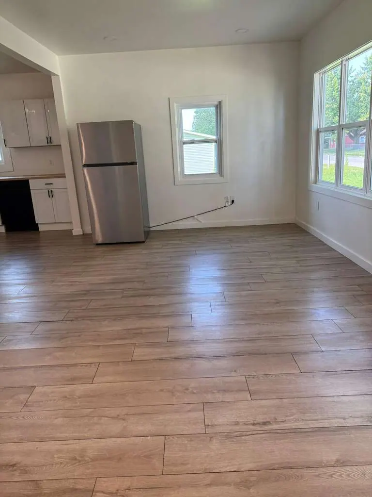 Wood-look plank flooring across a bright room that opens to the kitchen