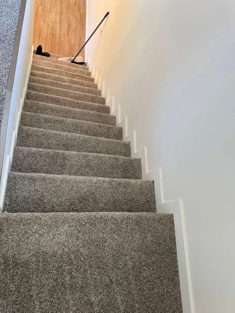 Staircase with new gray carpet and white stepped trim