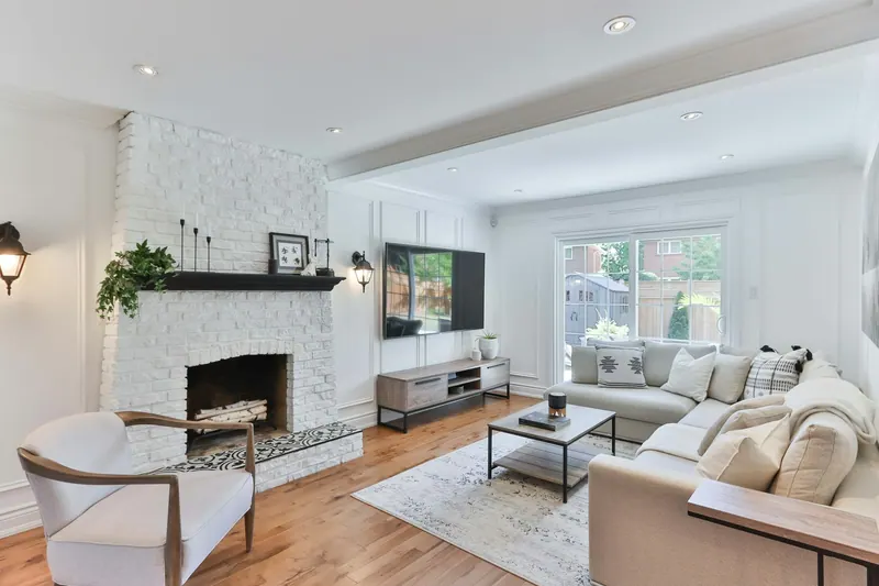 Renovated living room with a white brick fireplace and wood floors