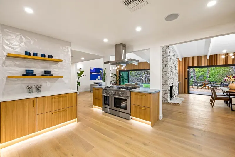 Wood kitchen with a stainless range, a white textured backsplash, floating shelves and under-cabinet lighting