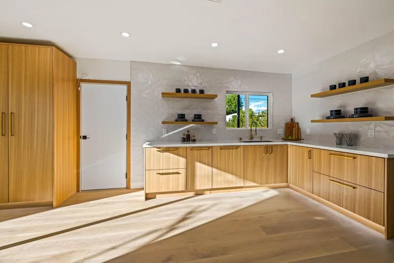 Wood kitchen with white countertops, floating shelves and light oak flooring in afternoon sun
