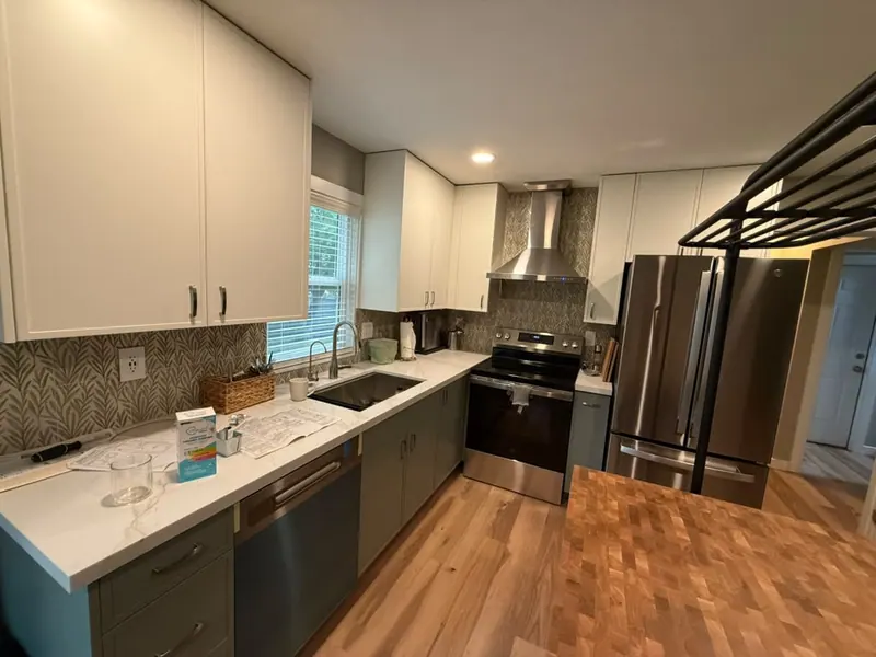 Updated kitchen with two-tone cabinets, light countertops, stainless appliances and a patterned backsplash
