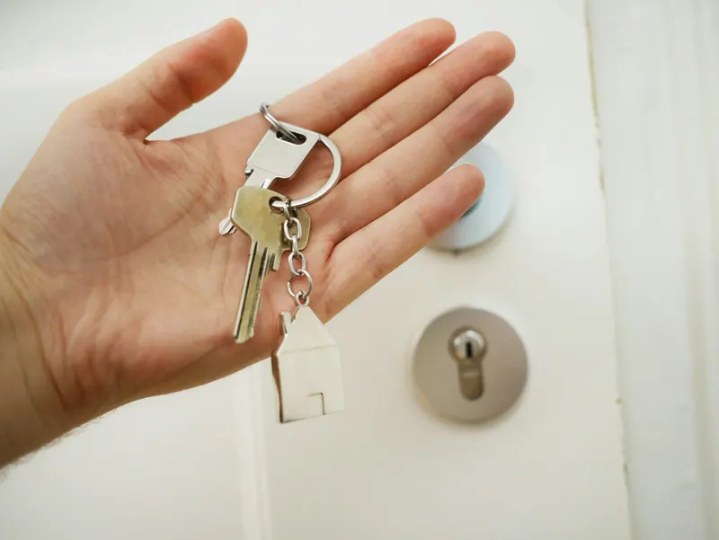 Hand holding keys in front of a door lock