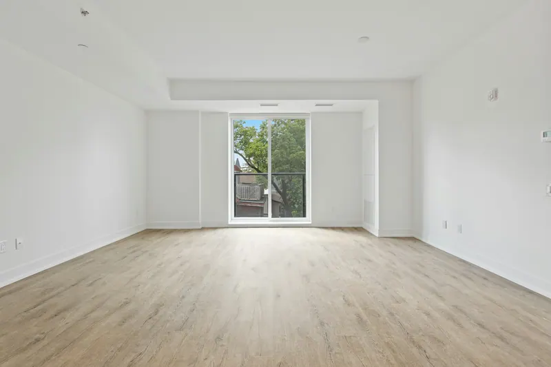 Empty newly built room with light vinyl plank flooring and a glass door