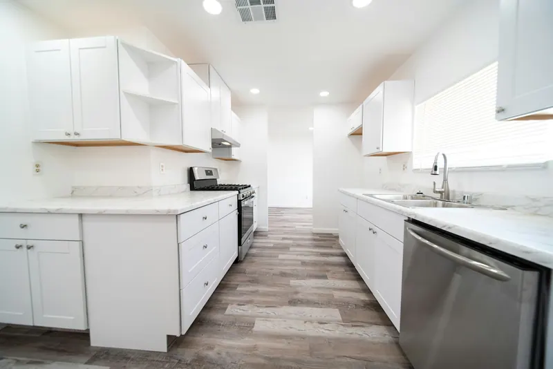 New galley kitchen with white cabinets and a stainless dishwasher