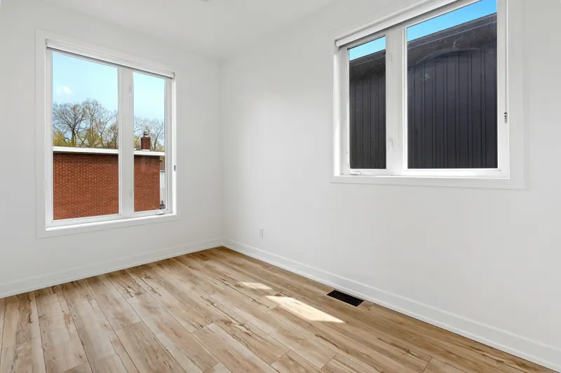 Empty new room with two windows and wood-look flooring