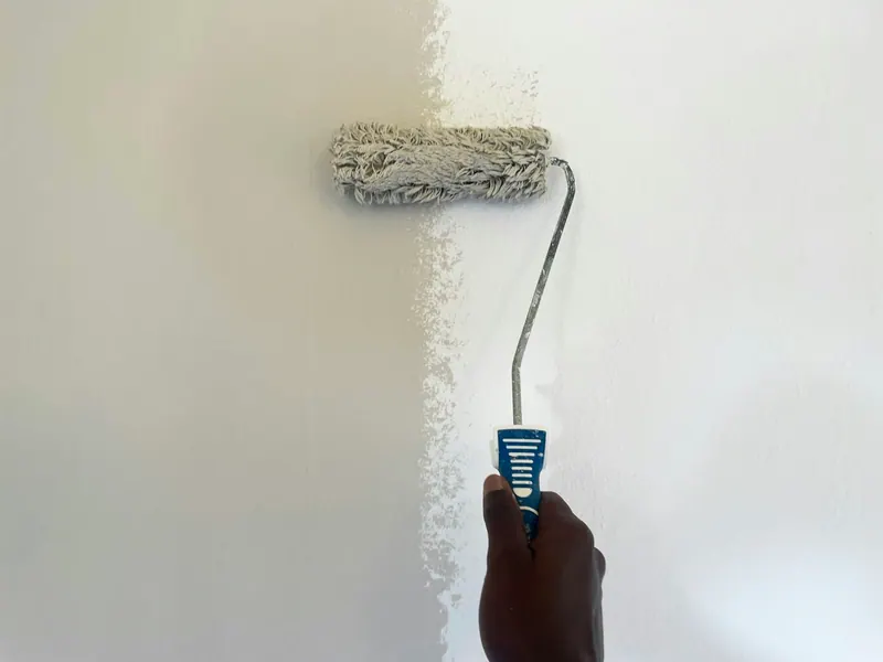 Hand rolling white paint onto a wall