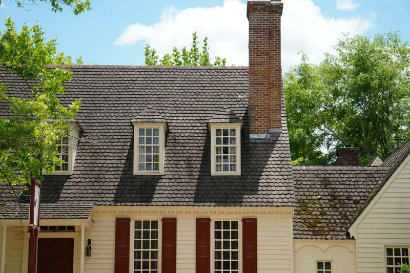 Colonial-style house with a shingle roof, dormers and a brick chimney