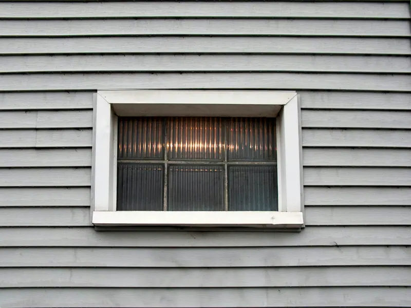 Gray lap siding around a window with white trim